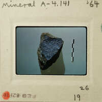 Small blue gemstone on white surface with measurement markings.