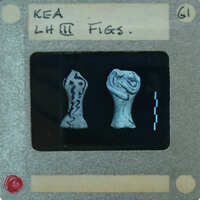 Two small figurines on a display card with labels and measurements.