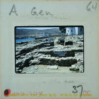 A photograph of ancient ruins with a body of water and mountains in the background.