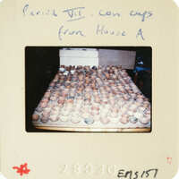 Photograph of clay pots drying on racks.