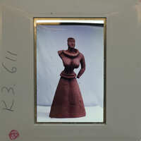 A clay sculpture of a person with an elongated body displayed on a white stand K3.611