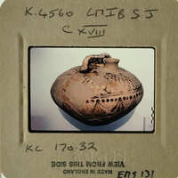 A photograph of an ancient clay pot with intricate designs on display.