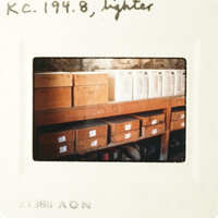 A photograph of a wooden shelf filled with boxes, taken from an angle above the items.