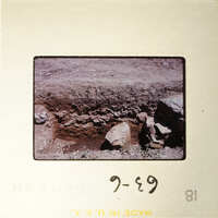 This is an image of a rock formation with dirt and vegetation, captured on a film strip.