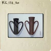 Two ceramic vases on a white surface, with one being larger and having handles.