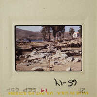 A photograph of a rocky landscape with trees and a building, taken on an old film negative.