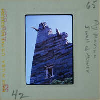 An old, stone tower with a pointed roof and windows.