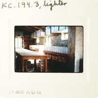 An old photo captures an interior space with a table, shelves, and a window.