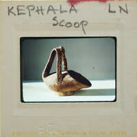 An image of an old, brown clay pot on a white surface with a label that reads "KEPHALA SCOOP".