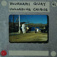 Old photograph of a dock with boats and people, labeled "YOURKI QUIAY UNLOADING CAIQUE".