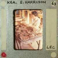 A vintage photo of a woman working with pottery, set against a backdrop of her workspace.