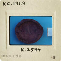 "A photograph of an object on a blue surface with a label and numbering."