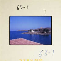 View of a coastal town with water and buildings under a blue sky.