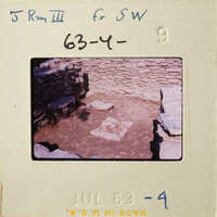 Stone ruins with dirt and vegetation, viewed from above.