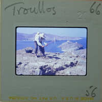 Man working on a rocky cliff by the sea.