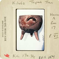 This is an image of a clay pot with a handle and a hole at its base, displayed on a white surface.