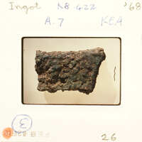 Photograph of an object with a rusted surface, possibly metal, on a white background.