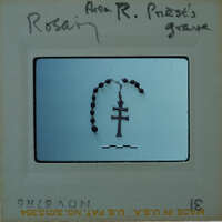 A black and white photograph of a rosary with a cross