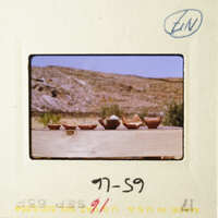 A photograph of a wooden table with four bowls on it, set against a desert landscape.