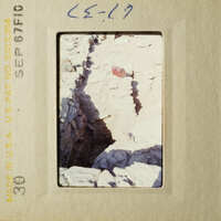 A photograph of an archeological site with stone ruins and a small hole in the ground.