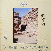 Old stone ruins with blue sky and desert ground.