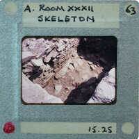 A photo of a room with stone walls and floor, displayed on an old film strip labeled "A ROOM XXXII".