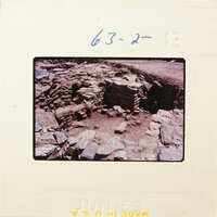 Old photograph of an archaeological site with ruins and scattered stones.