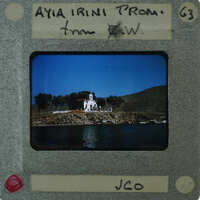 A vintage photo of a coastal town with a church on a hillside, enclosed by a film strip frame.
