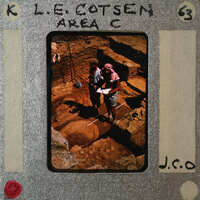 The image is a photograph of two people standing on an archaeological site, with the photo itself appearing to be placed within a film strip frame.