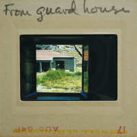 Picture of a guard house with a view of a building and grass through the window.