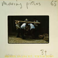 Men working together to move a large object on a wooden pallet.