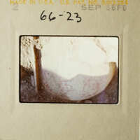 An aged photograph of a rock with a hole, taken from above.