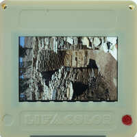 A small, colorful digital camera displaying a photo of an old stone structure.