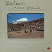 A large balloon on the ground with people standing around it.