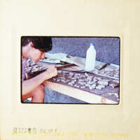 Woman working on art project at table with various materials.