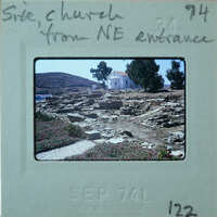 White church in center surrounded by stone wall remains