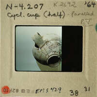 Ancient Greek vase with intricate design, photographed and labeled as "CUP HALF" on a museum card.