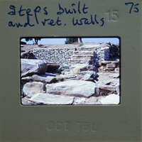 The image is a photograph of an old stone structure, possibly ruins, with a focus on the steps and walls made of stacked stones.