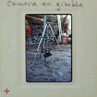 Camera tripod with camera on top, set up outdoors.