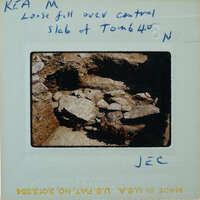 A vintage photograph of a cave entrance with jagged rocks and handwritten notes on the back.