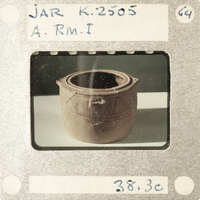 A clay pot with a handle and markings on it, photographed against a white background.