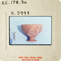 Ancient ceramic bowl with visible cracks and damage, photographed against a blue background.