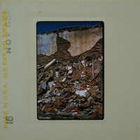 The image shows a destroyed building with debris scattered around, captured on a film negative.