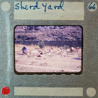 A vintage photo of a group of people working on a field with rocks, set within an old film strip frame.