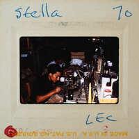 Person working at a table with various objects, possibly crafting or repairing items.