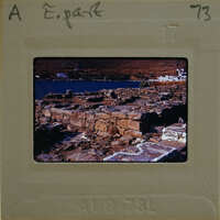 A vintage film strip showing an image of ancient ruins by a body of water, with the number "73" visible on the border.