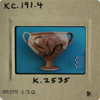 Ancient Greek vase with intricate designs, photographed against blue background.