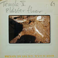 Muddy dirt floor with a line of white between the floor and the stone wall.