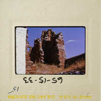 Old, crumbling stone ruins with vegetation under a clear sky.
