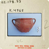 Ancient ceramic pot with visible cracks and chips, photographed on a white surface.